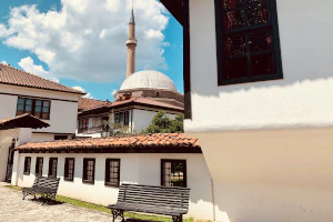 Innenhof des Komplexes der Albanischen Liga von Prizren im Kosovo mit Blick auf das Minarett und die Kuppel der Sinan-Pascha-Moschee im Hintergrund.