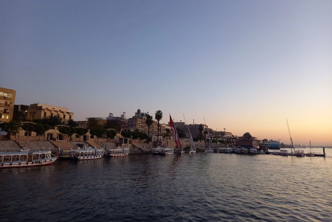 Nilufer in Luxor bei Abenddämmerung mit Feluken und Kreuzfahrtschiffen