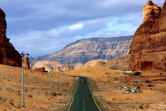 Asphaltierte Straße durch die Wüstenlandschaft von Al 'Ula mit Sandsteinfelsen und Bergen in Saudi-Arabien.